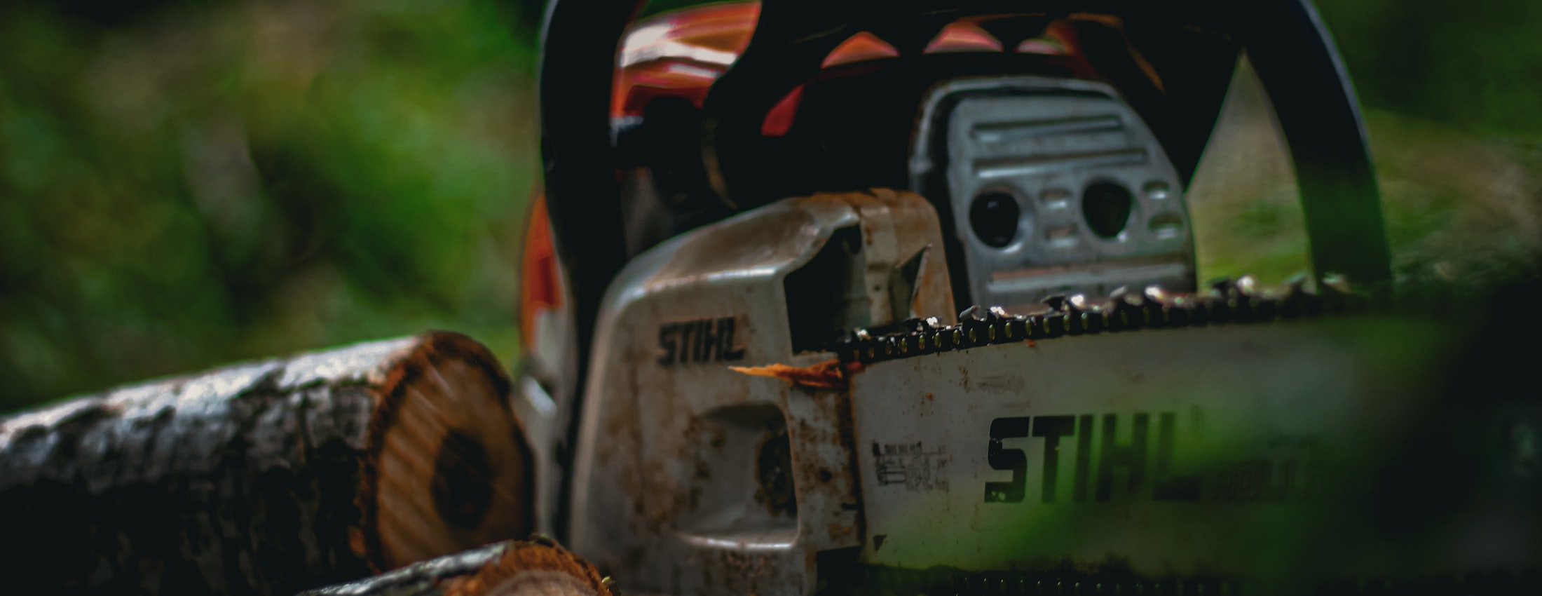 A well-used STIHL chainsaw resting on freshly cut logs